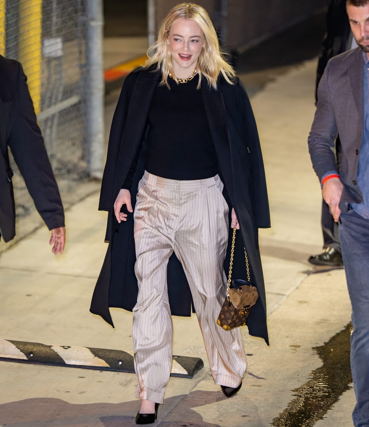 Emma Stone carrying a monogram Louis Vuitton bag and wearing black pointed-toe heels to finish off her look