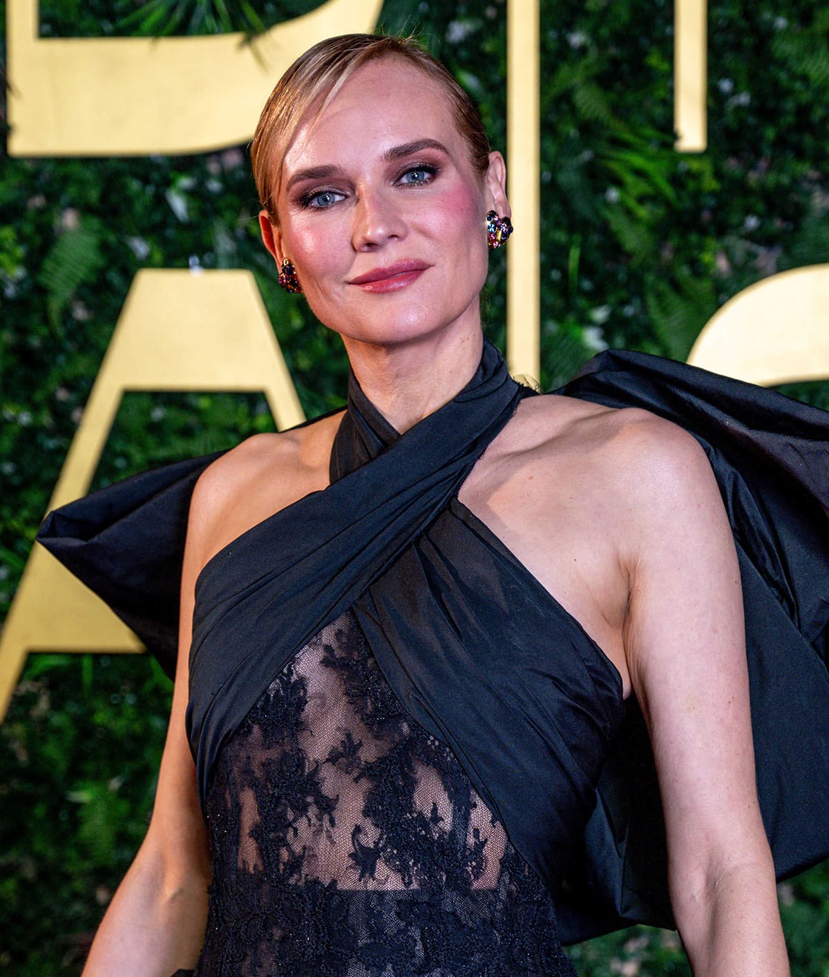 Diane Kruger styles her blonde hair in a neat side-parted updo and highlights her lovely features with smokey eyeshadow, rosy blush, and pink lipstick