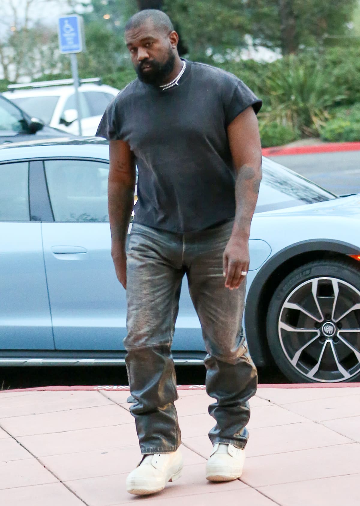 Kanye West keeps things casual in a black tee, distressed jeans, and white sneakers for his son Saint's basketball practice