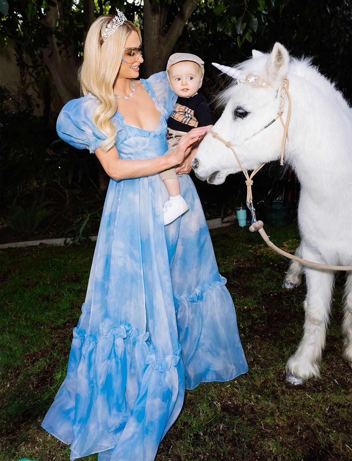 Paris Hilton and son Phoenix petting a white pony dressed as a unicorn from Itty Bitty Petting Zoo