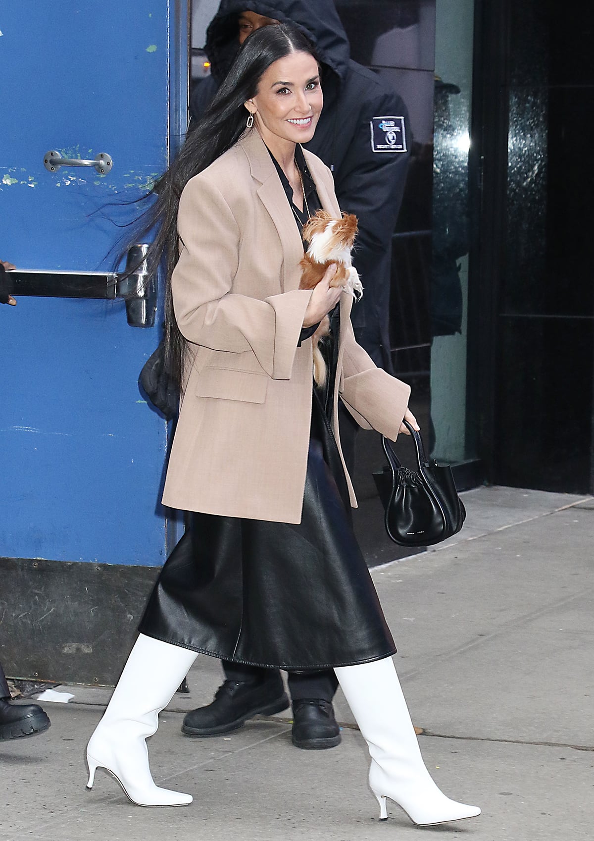 Demi Moore promotes her new FX series Feud: Capote vs. The Swans in a neutral winter outfit, including an oversized beige blazer, a black leather midi skirt, and white knee-high boots, at Good Morning America studios on January 31, 2024