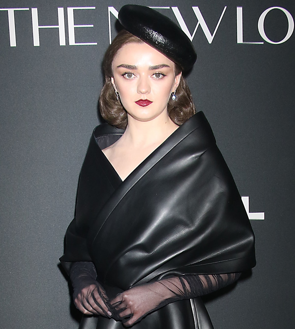 Maisie Williams looks straight out of the 1940s as she wears pin curls and burgundy red lipstick with an angled beret and sheer gloves