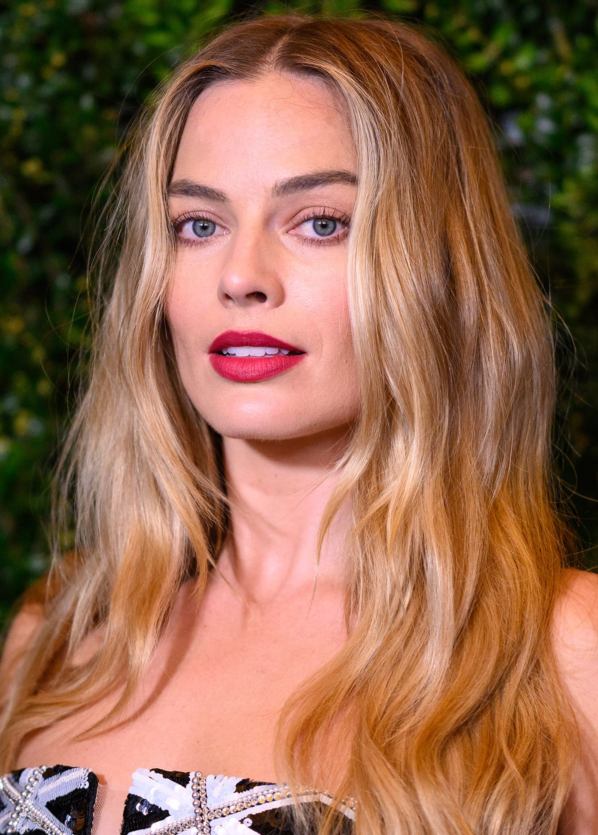Margot Robbie styles her long blonde hair in sultry waves and wears hot pink lipstick