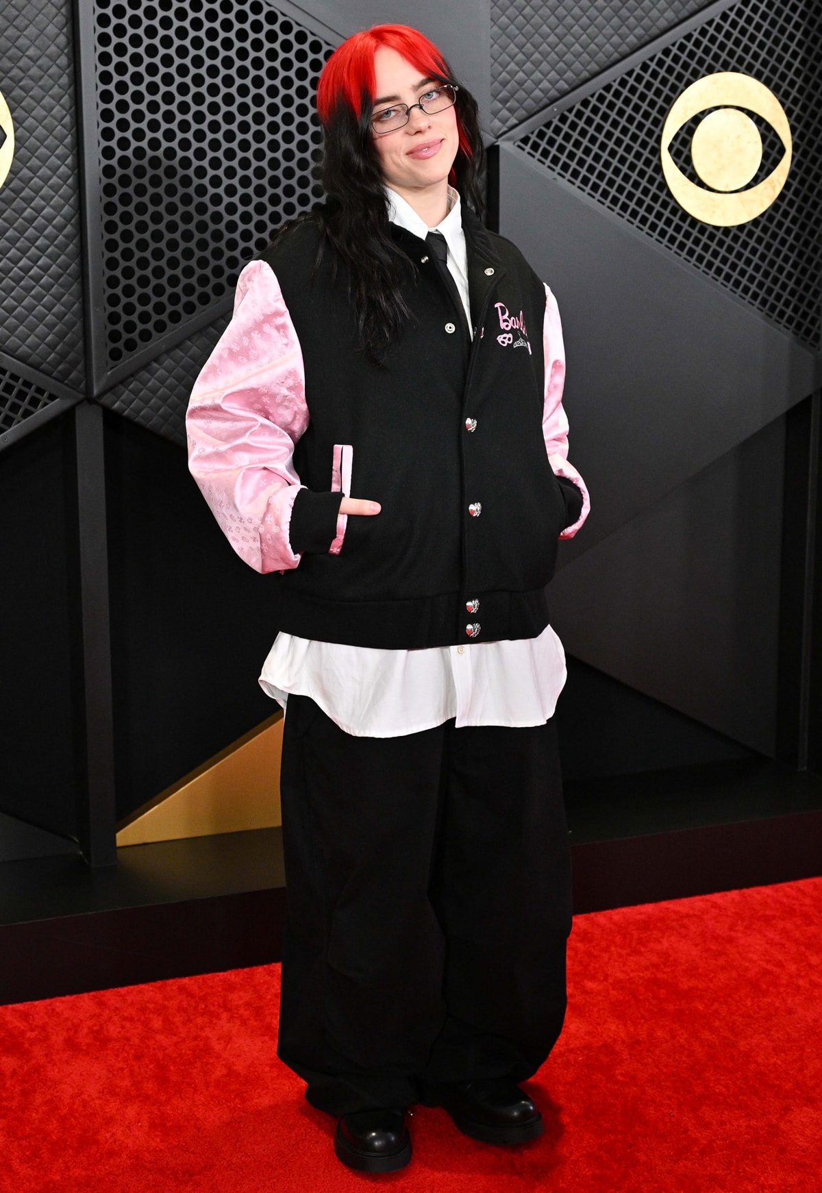 Petite singer Billie Eilish attended the 2024 Grammy Awards vintage Barbie-themed Chrome Hearts bomber jacket, rocking pink sleeves and "Barbie" embroidery with a casual white button-down and black pants