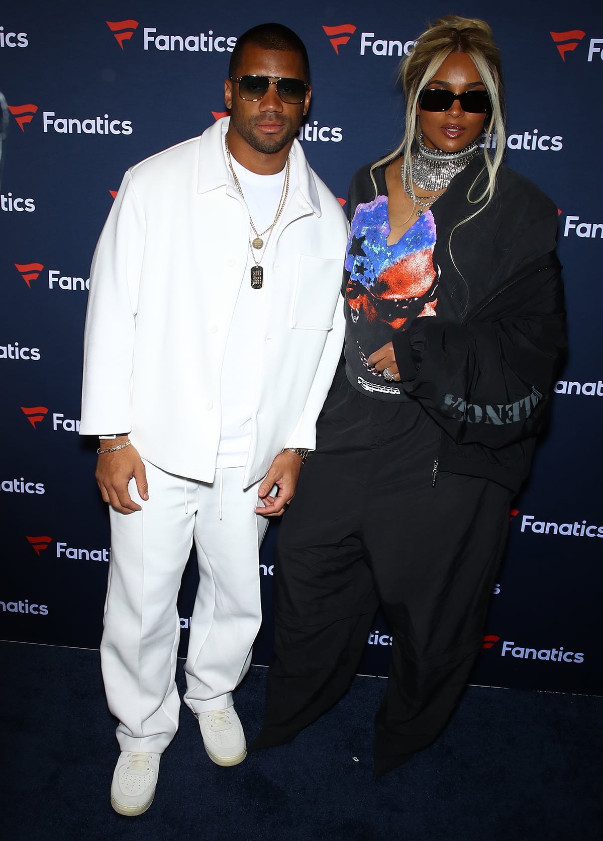 Russell Wilson and Ciara wear cool outfits to Michael Rubin’s Fanatics Super Bowl 2024 Party, with Russell in head-to-toe white and Ciara in a black Dennis Rodman tee, trousers, and Balenciaga jacket