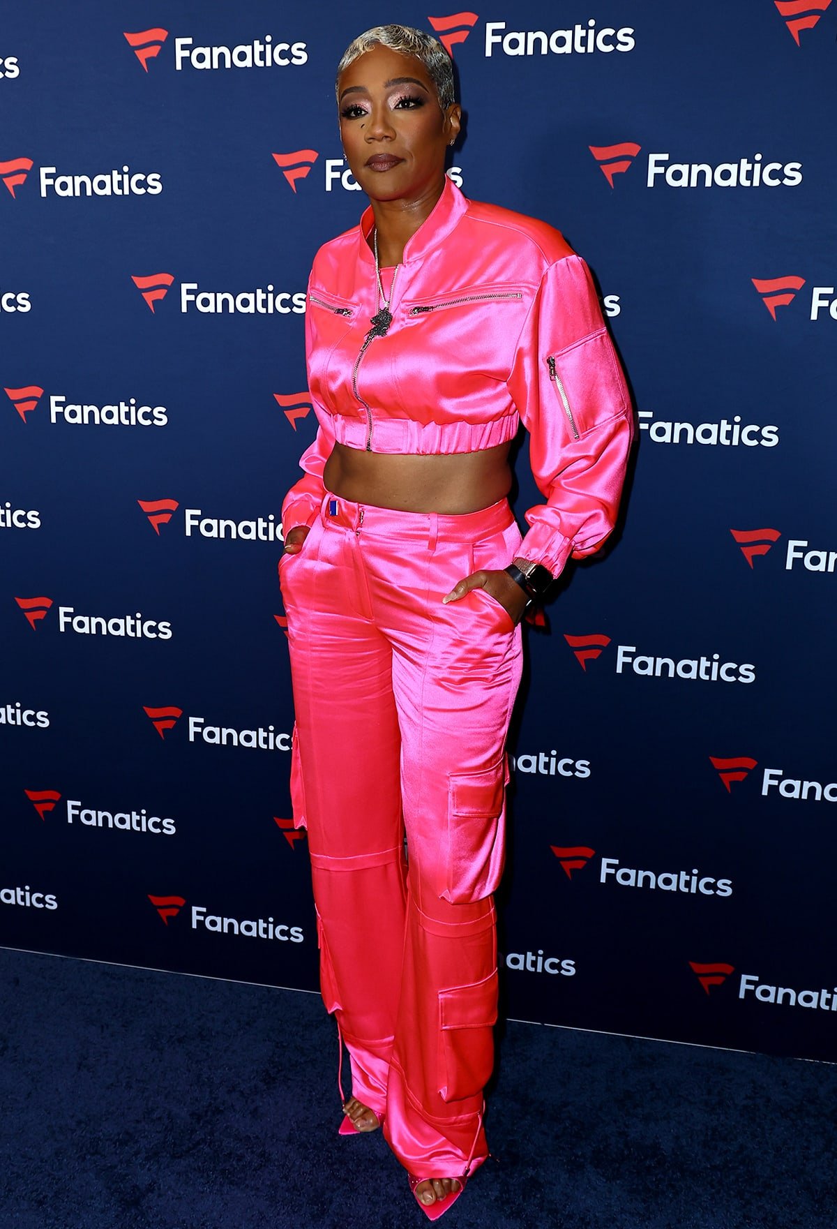 Tiffany Haddish turns heads in a neon pink crop jacket, matching cargo pants, and pink open-toe heels at Michael Rubin's Fanatics Super Bowl 2024 Party on February 10, 2024