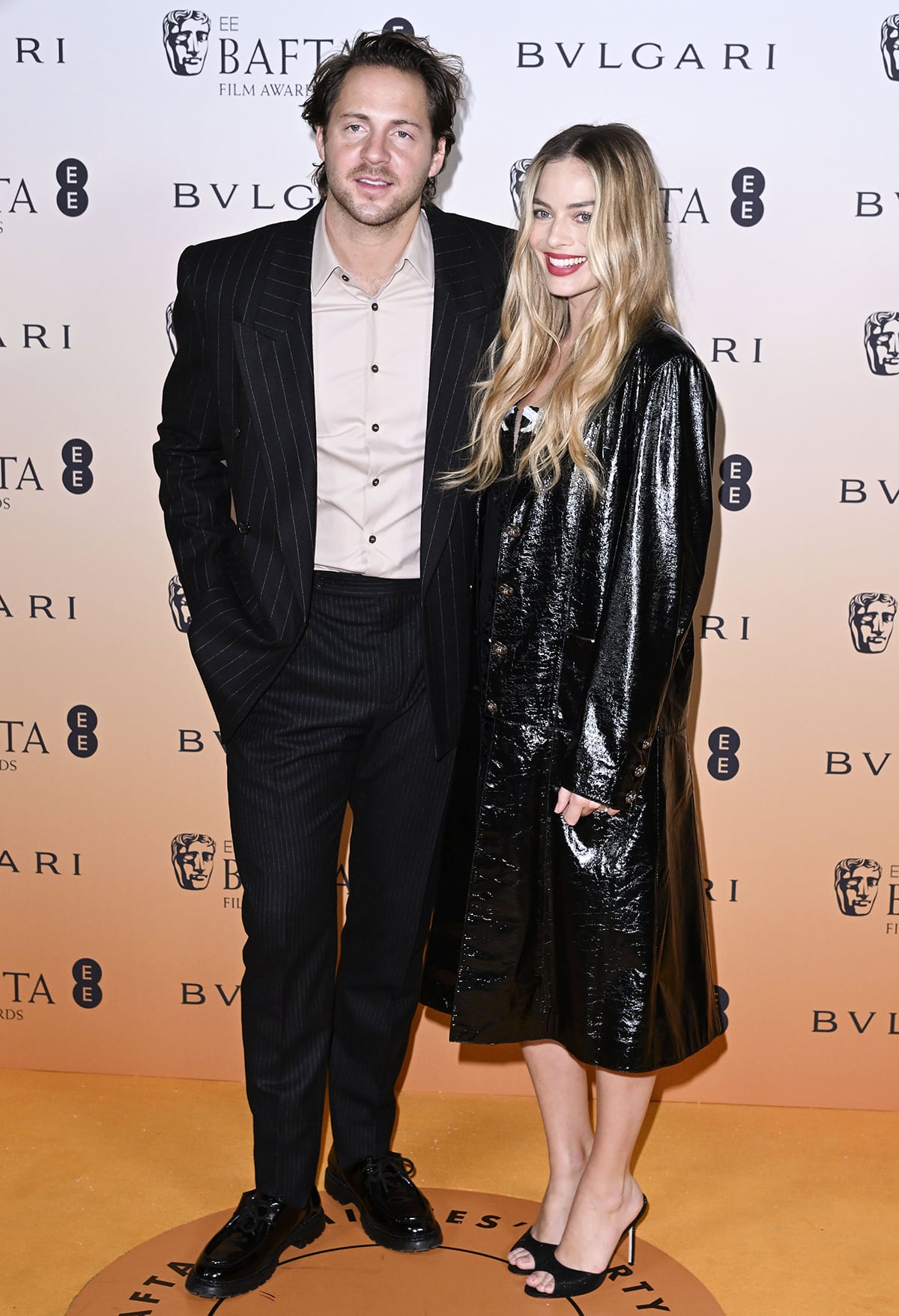 Margot Robbie with her husband Tom Ackerley dressed in a beige shirt with a black pinstripe suit and chunky oxford shoes