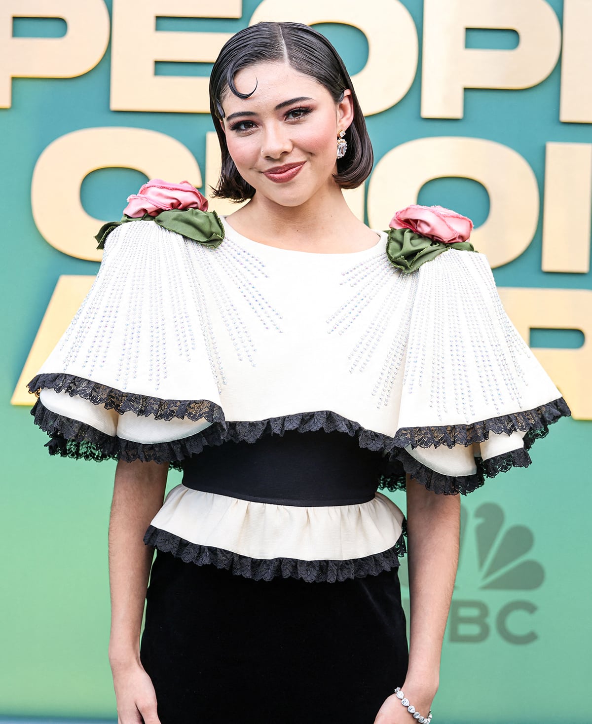 Xochitl Gomez's black and white Gucci dress features flouncy sleeves with pink and green flower corsages on the shoulders
