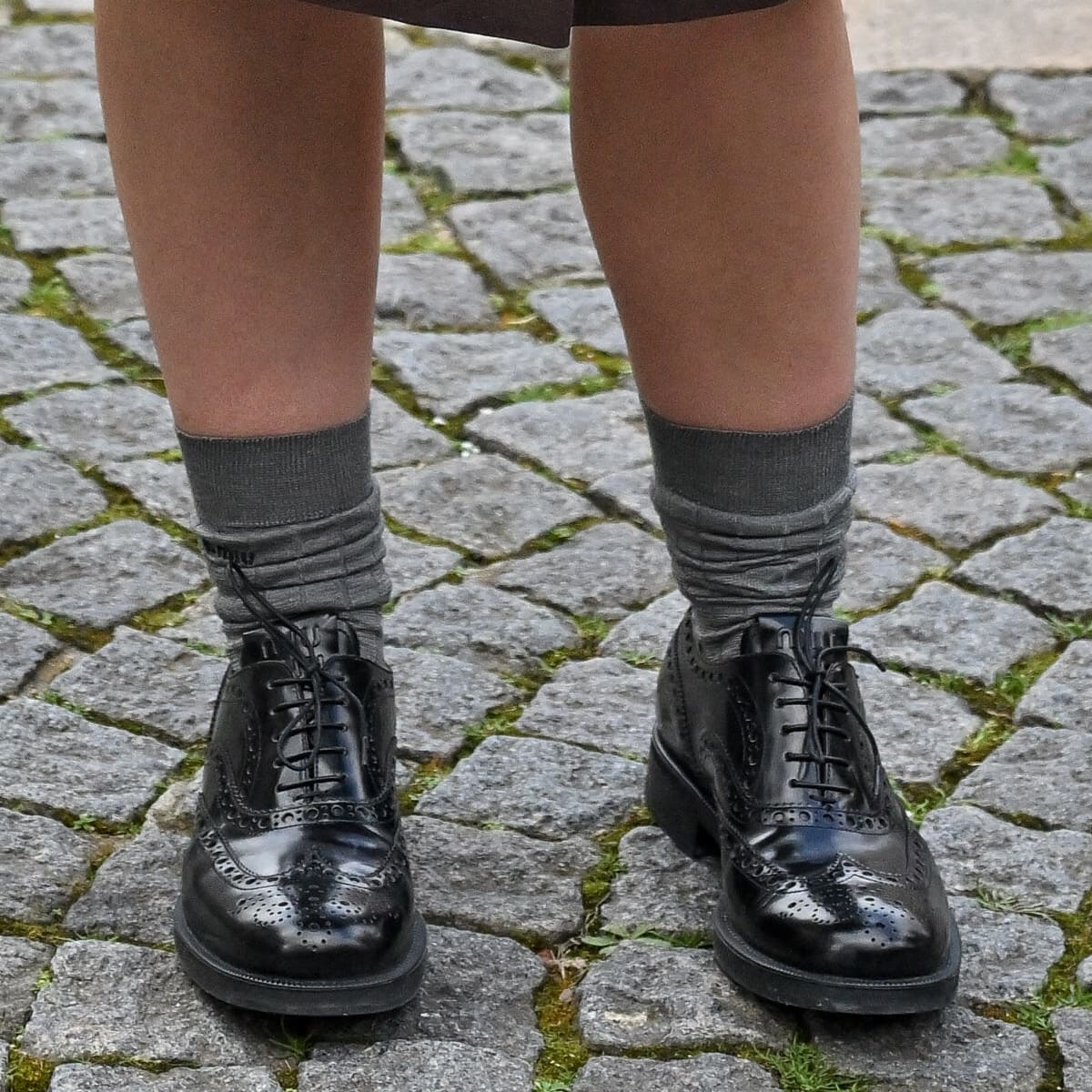 Elevating the academic aesthetic, Lorde steps out in Church’s x Miu Miu black leather Oxford brogues, complemented by scrunched gray socks, at Paris Fashion Week