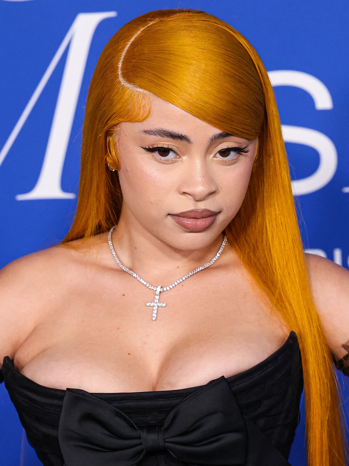 Ice Spice wears her orange hair sleek and straight with a side-parted swoop and highlights her striking features with winged eyeliner and brown lipgloss