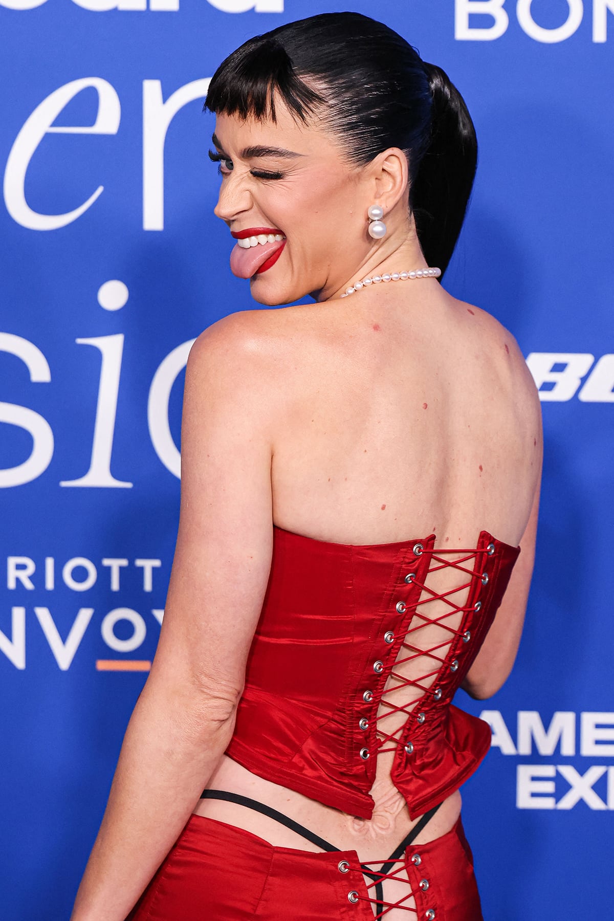 Katy Perry reveals her black G-string underwear and 3D butterfly prosthetic lower back tattoo in a red corset top and a low-waist skirt