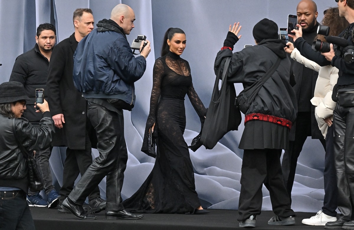 Kim Kardashian's dress, reminiscent of Morticia Addams, beautifully accentuates her famous curves, while the intricate lace detailing and the dramatic train trailing behind her add a touch of timeless allure