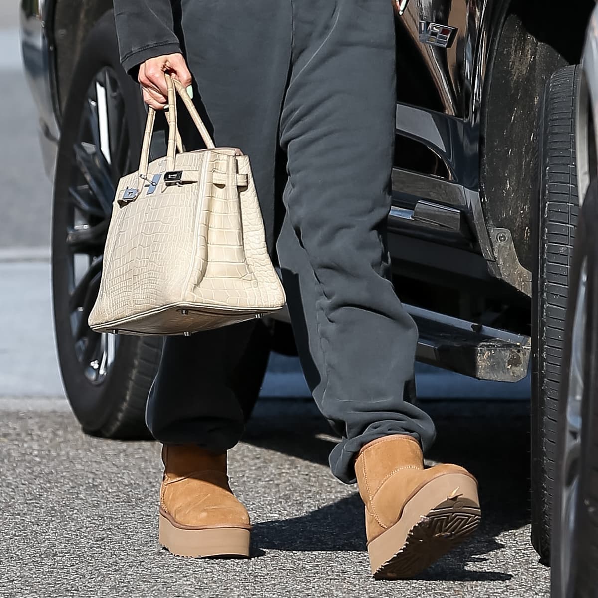 Jennifer Lopez paired UGG Classic Mini Platform Boots with a matte cream Hermes Birkin Crocodile Bag, showcasing a blend of casual comfort and luxury