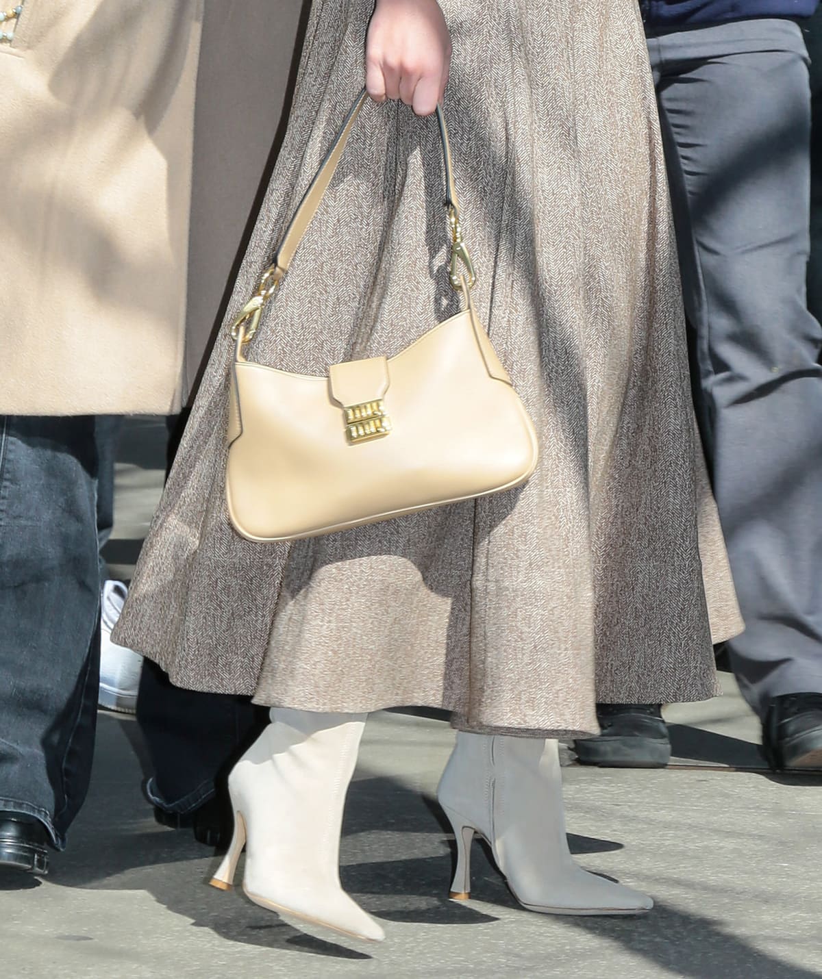 Sydney Sweeney opts for a monochromatic look, teaming her beige dress with cream-colored Staud boots and sand Miu Miu bag