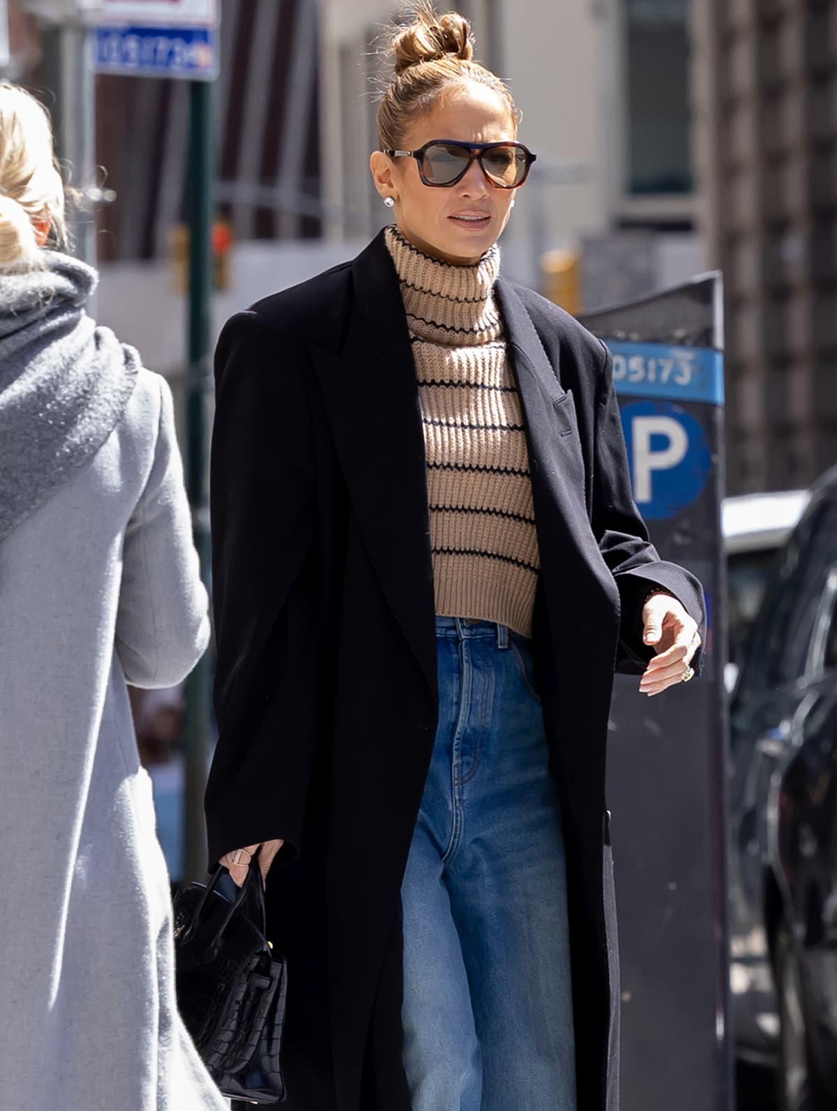 Jennifer Lopez is house-hunting in a long, black coat, striped turtleneck top, and wide-leg jeans