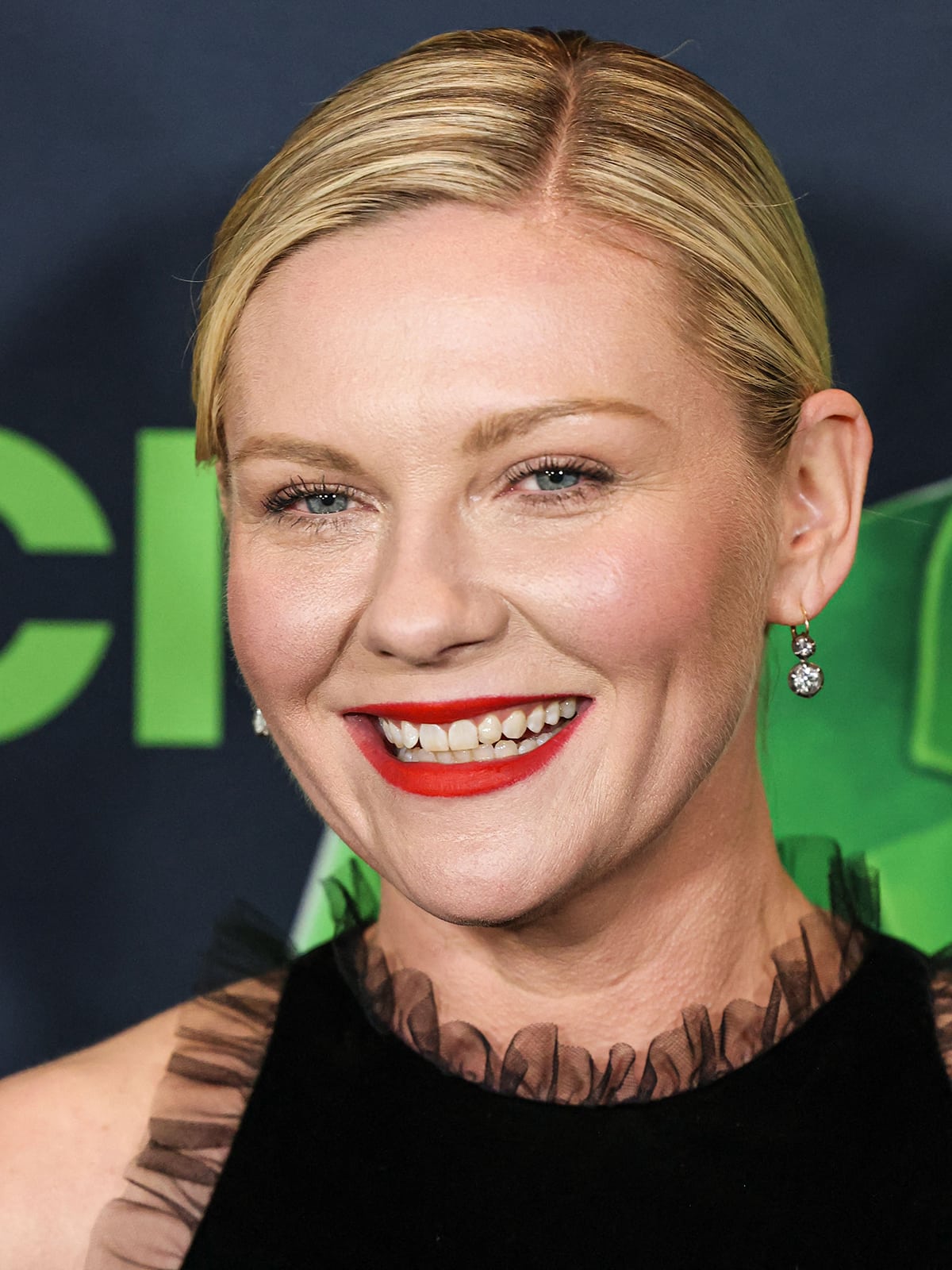 Accessorizing with Neil Lane diamond earrings, Kirsten Dunst completes her red carpet look with a neat side-parted updo and a swipe of bright red lipstick