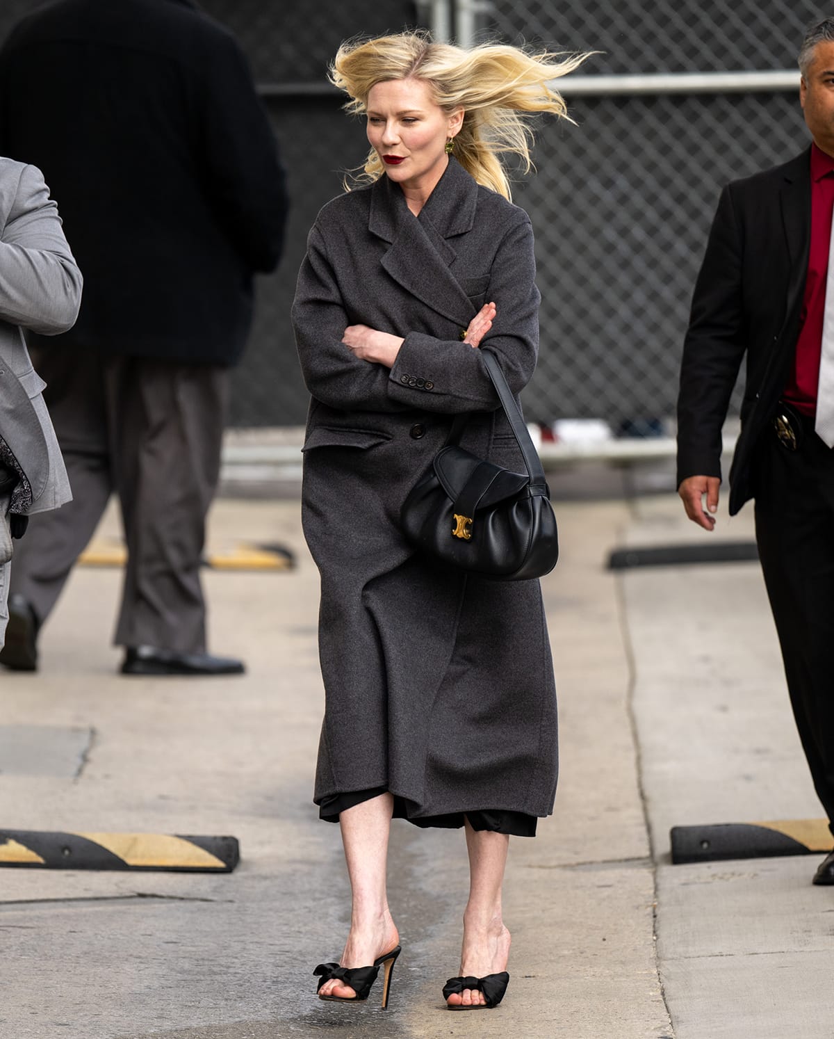 Kirsten Dunst heads to Jimmy Kimmel Live studios in an oversized gray coat, a black Lanvin dress, and a pair of black mules to discuss Civil War on April 4, 2024