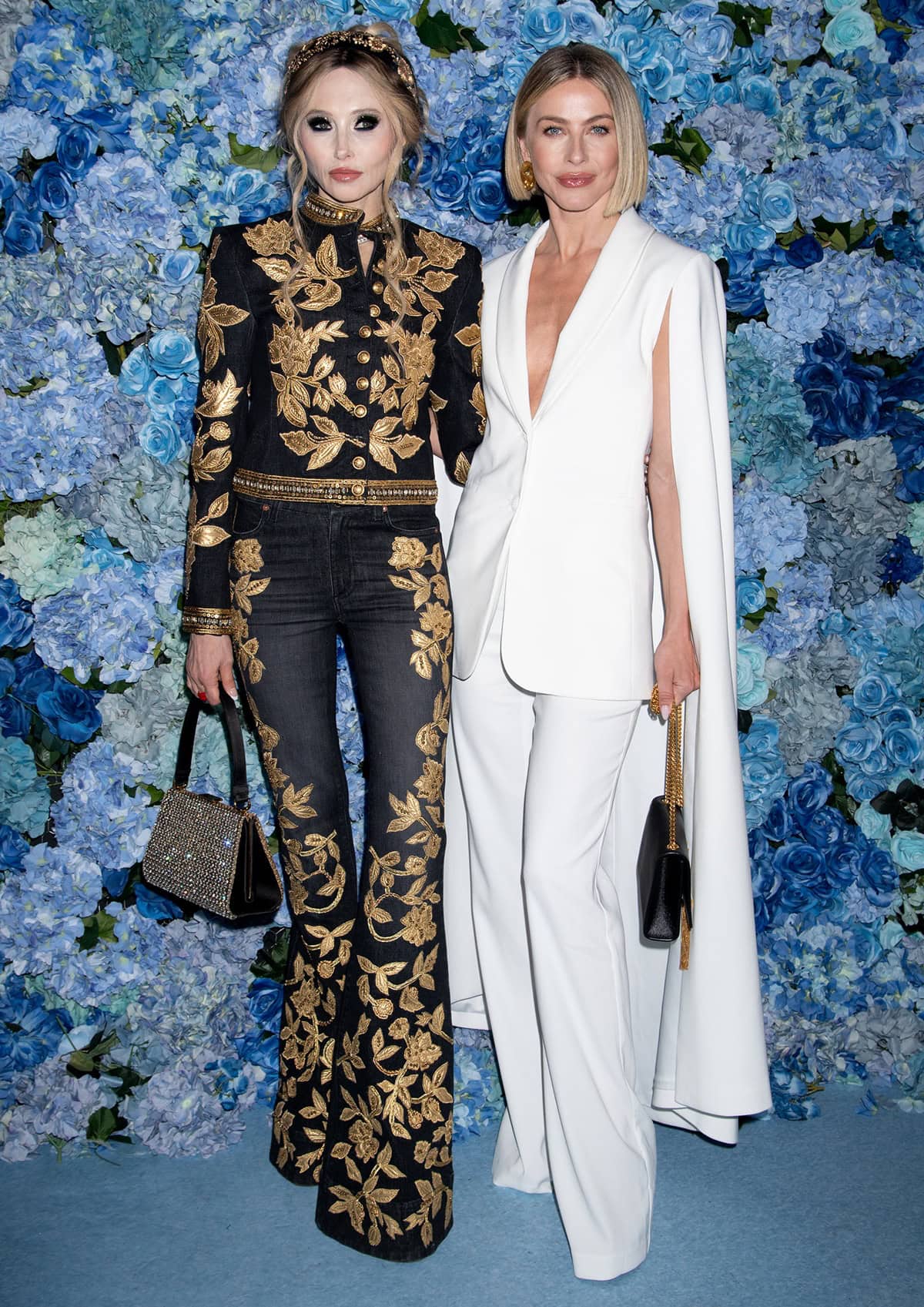 Stacey Bendet stuns in an opulent black and gold embroidered ensemble, while Julianne Hough exudes elegance in a sleek white cape blazer suit at the alice + olivia By Stacey Bendet Fall 2025 Presentation in New York City