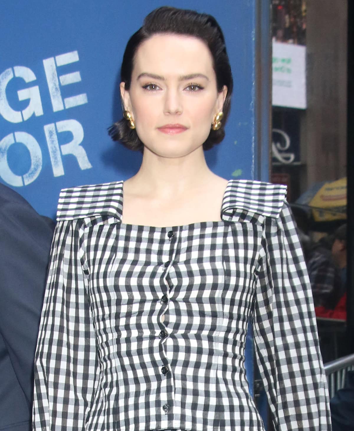 Daisy Ridley wears soft makeup and a slicked-back hairstyle and styles her outfit with Belperron gold jewelry