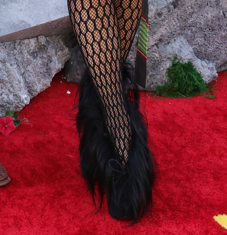 Gwen Stefani teams her green tartan outfit with black fishnets and furry ankle boots by Vivienne Westwood