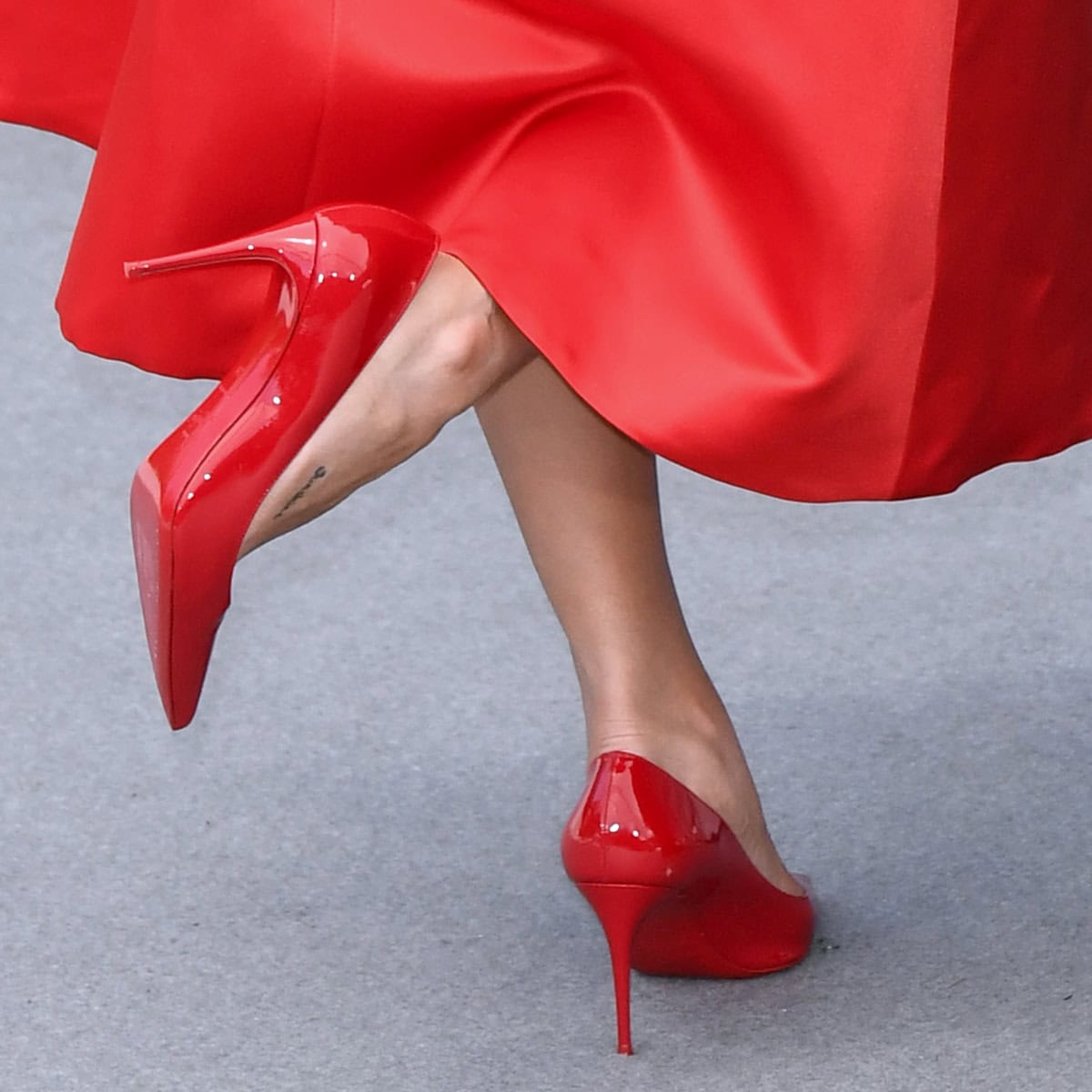 Selena Gomez flaunts the iconic red soles of her Christian Louboutin Kate pumps, perfectly complementing her scarlet Giambattista Valli dress at the Cannes Film Festival