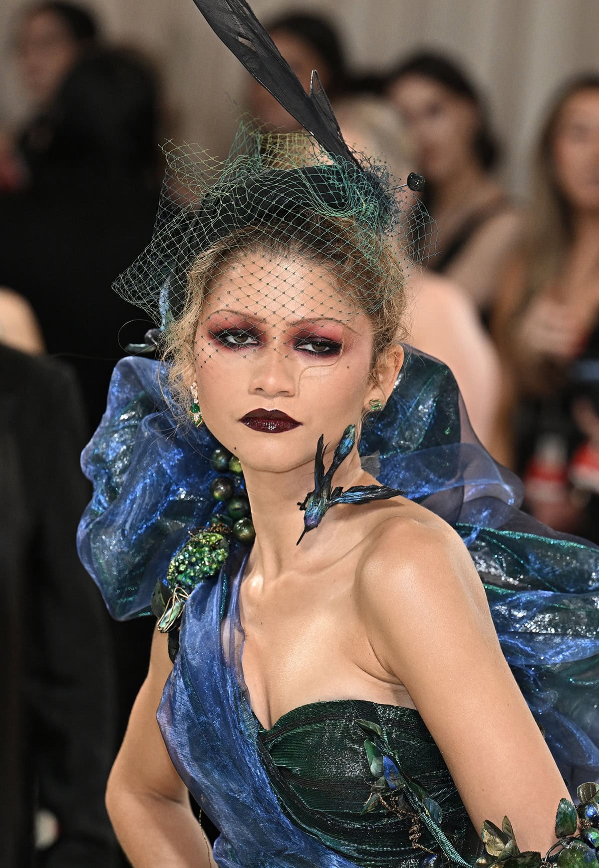 Zendaya keeps the villainous look going by wearing smokey red eye makeup and vampy lipstick