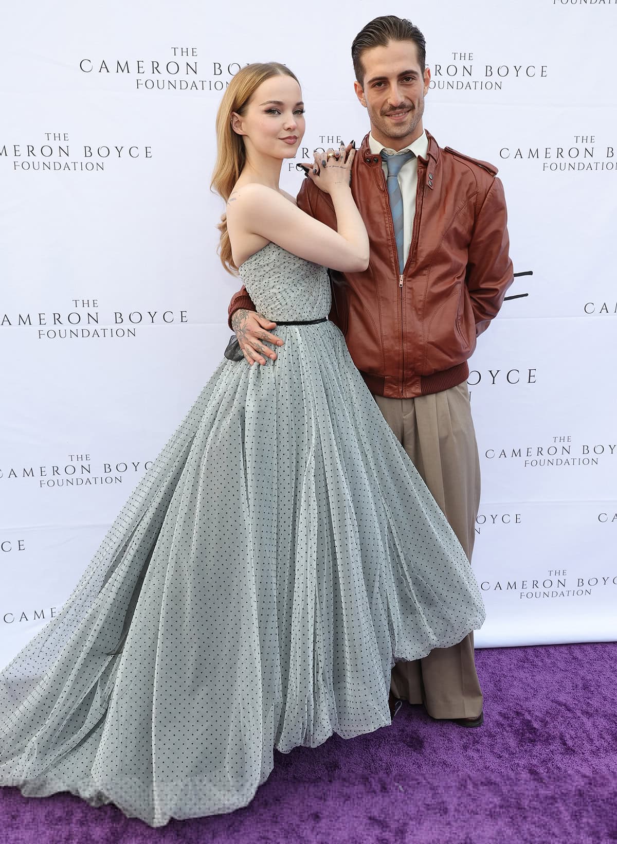 Dove Cameron is joined on the red carpet by her boyfriend Måneskin frontman Damiano David, who looks handsome in a brown leather jacket, white shirt, blue necktie, and baggy trousers