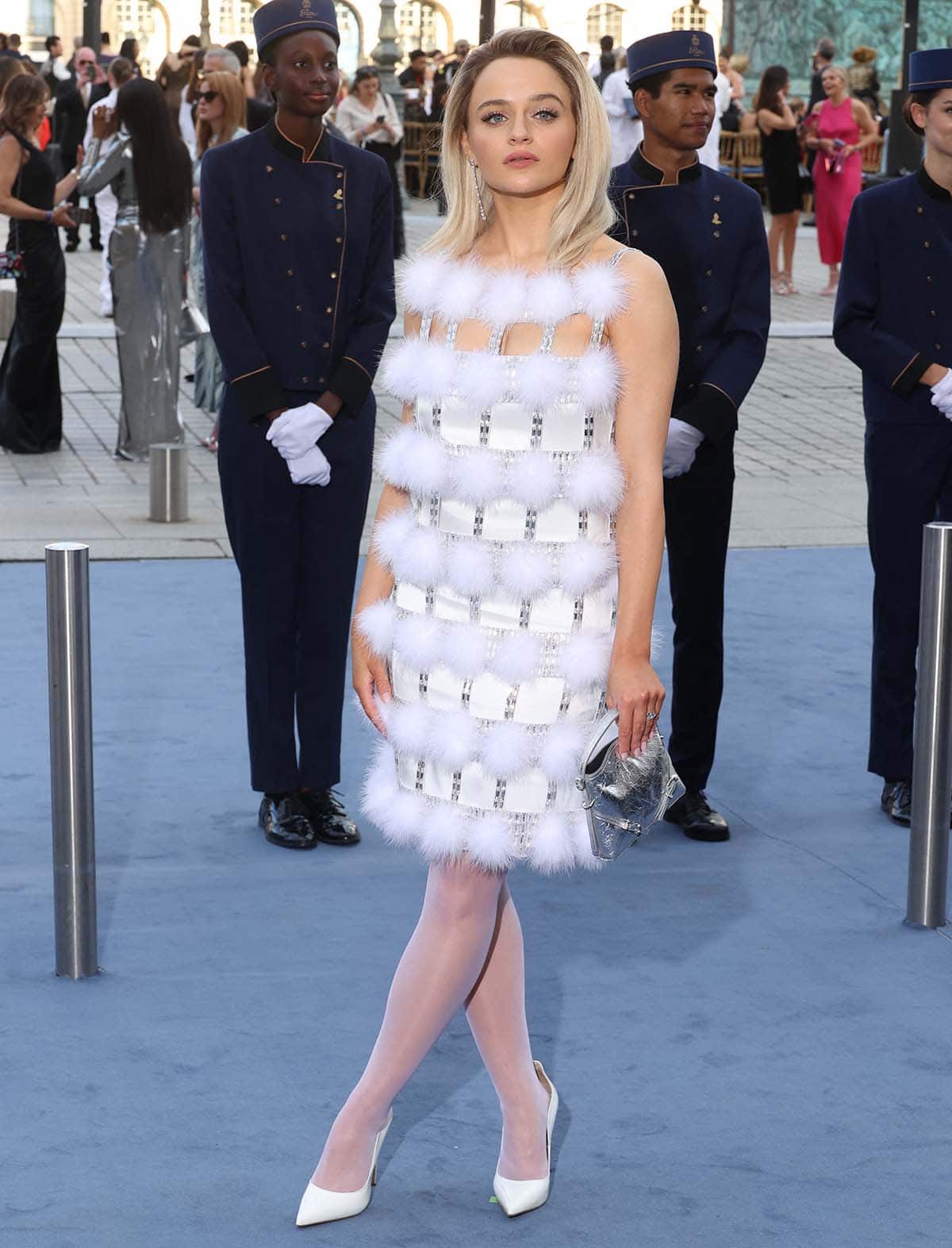 Joey King stuns in a space-age Givenchy mini-dress featuring a crystal-encrusted cage-like overlay with white pom poms at the 2024 Vogue World: Paris