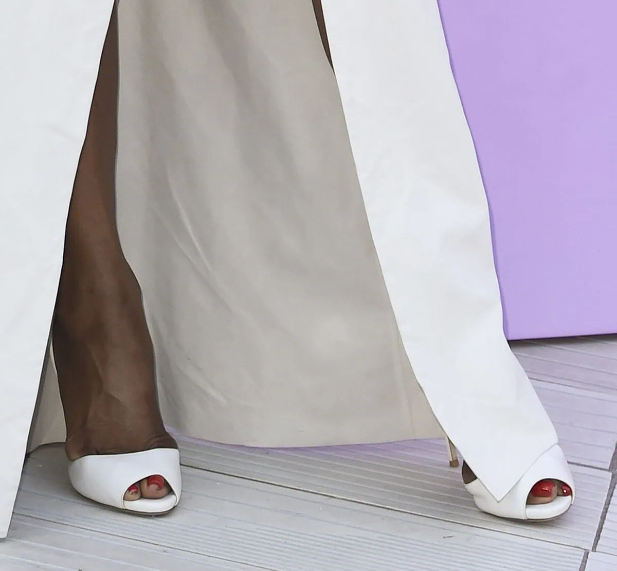Naomi Campbell completes her monochromatic white ensemble with white peep-toe pumps that look too small for her size 9 feet