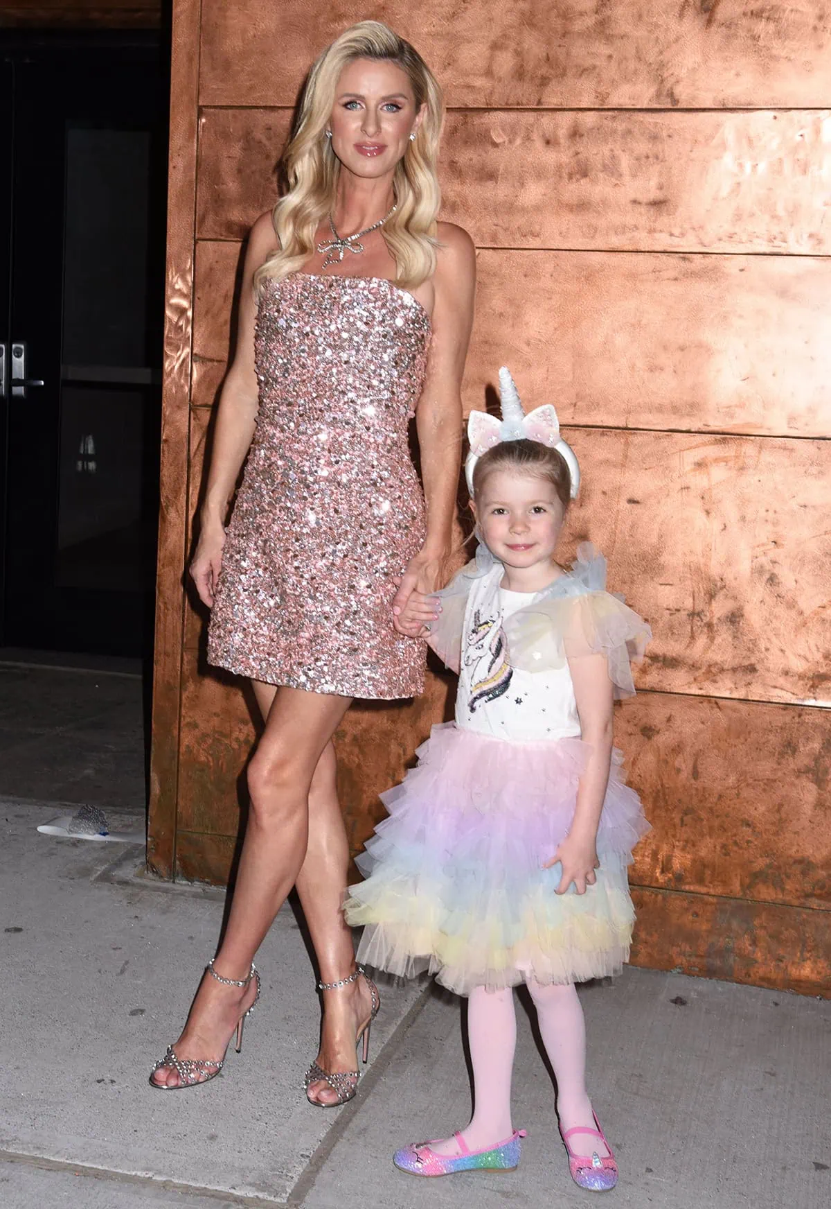 Nicky Hilton wears a glittery pink strapless mini dress by Alice + Olivia as she celebrates the LGBTQIA+ community with her daughter Teddy at Stacey Bendet’s annual Pride party in New York City
