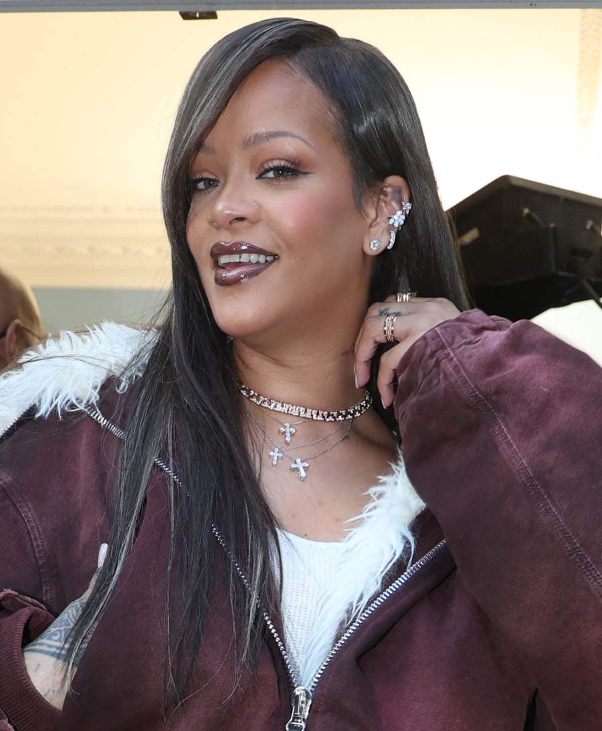 Rihanna wears a long, brunette wig with gray streaks and highlights her upturned eyes with bronze eyeshadow and cat eyeliner