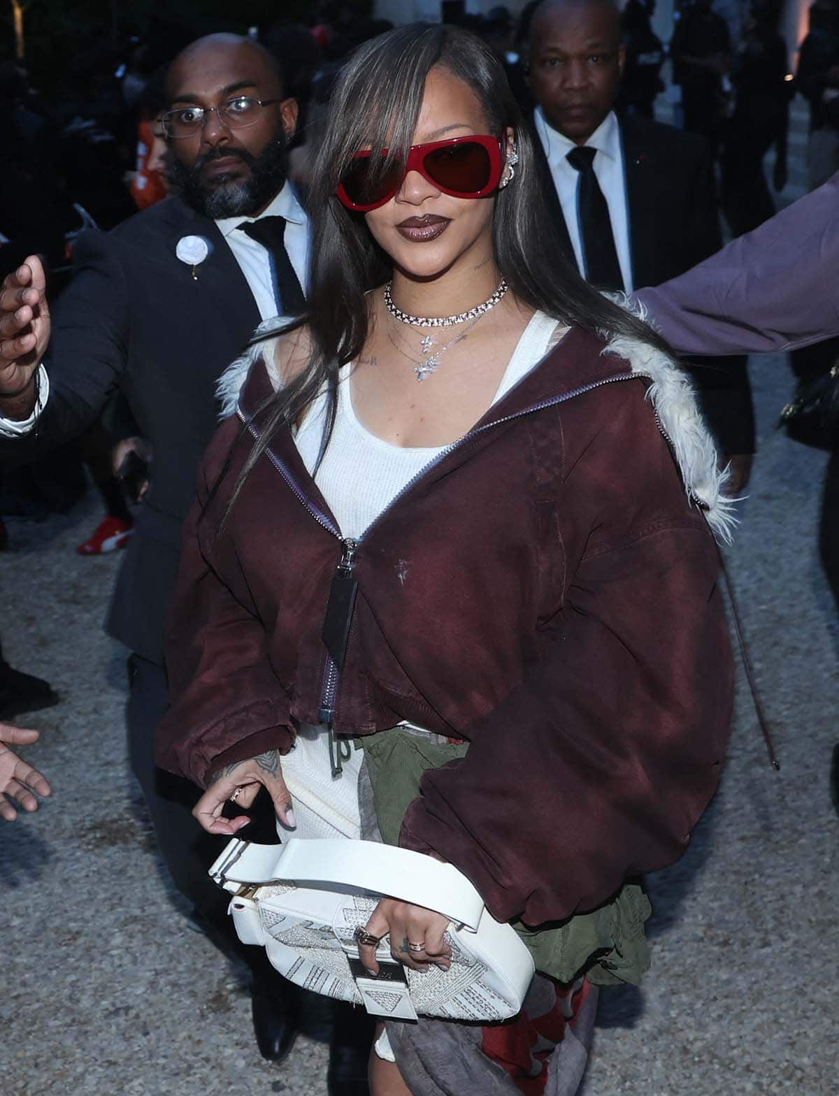 Rihanna carries her f-row essentials in a vintage white Dior Columbus bag and covers her eyes with red Linda Farrow x The Attico aviators