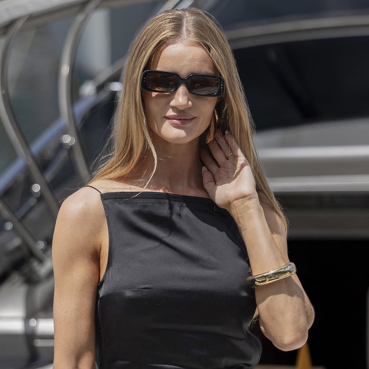 Rosie Huntington-Whiteley exudes understated elegance with her Tiffany & Co. gold bangle and subtly hidden statement earrings, perfectly complementing her chic black ensemble at the Jacquemus 2024 Cruise fashion show