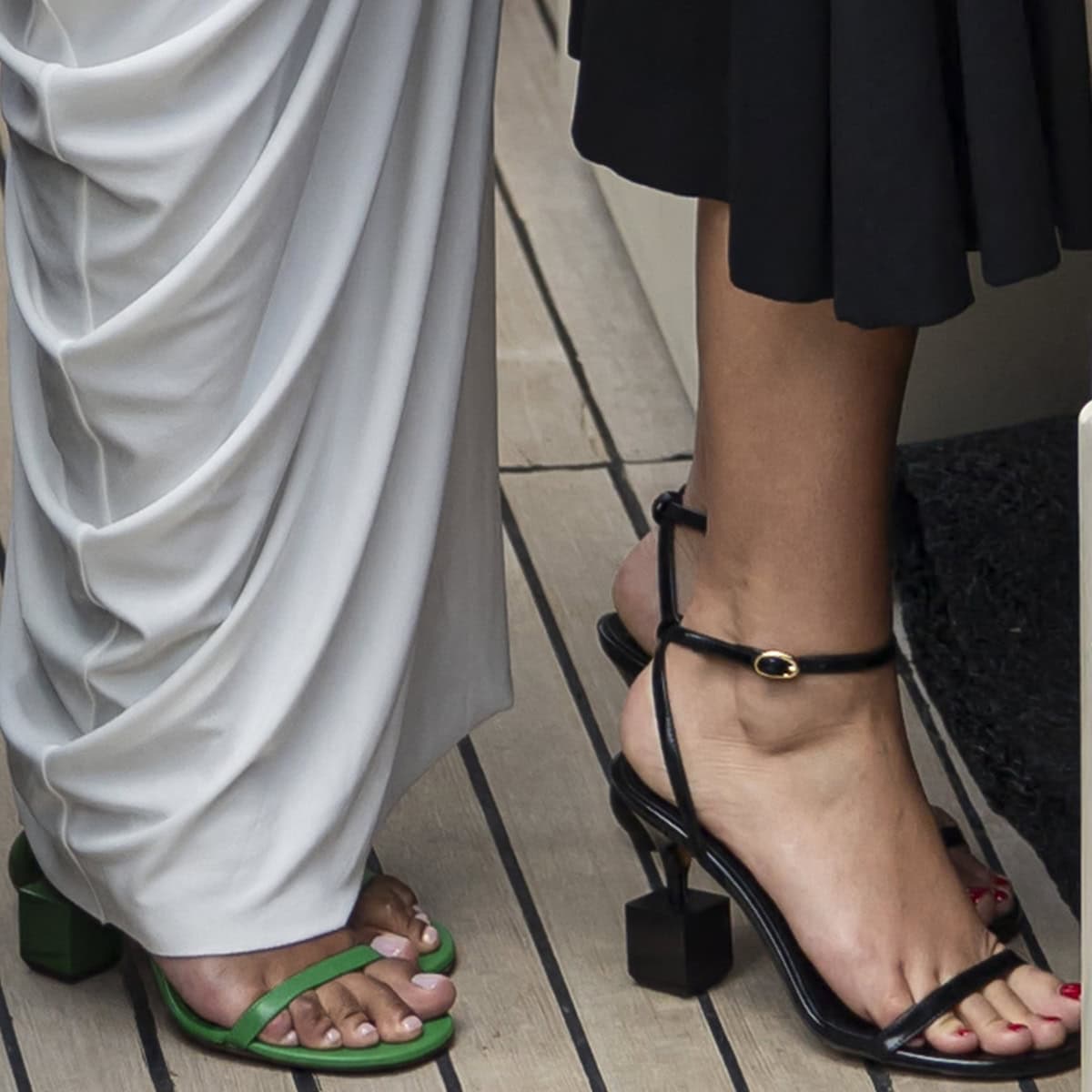 Tina Kunakey and Adèle Exarchopoulos showcase stylish footwear with Tina in vibrant green square-toe sandals and Adèle in elegant black ankle-strap heels at the Jacquemus 2024 Cruise fashion show