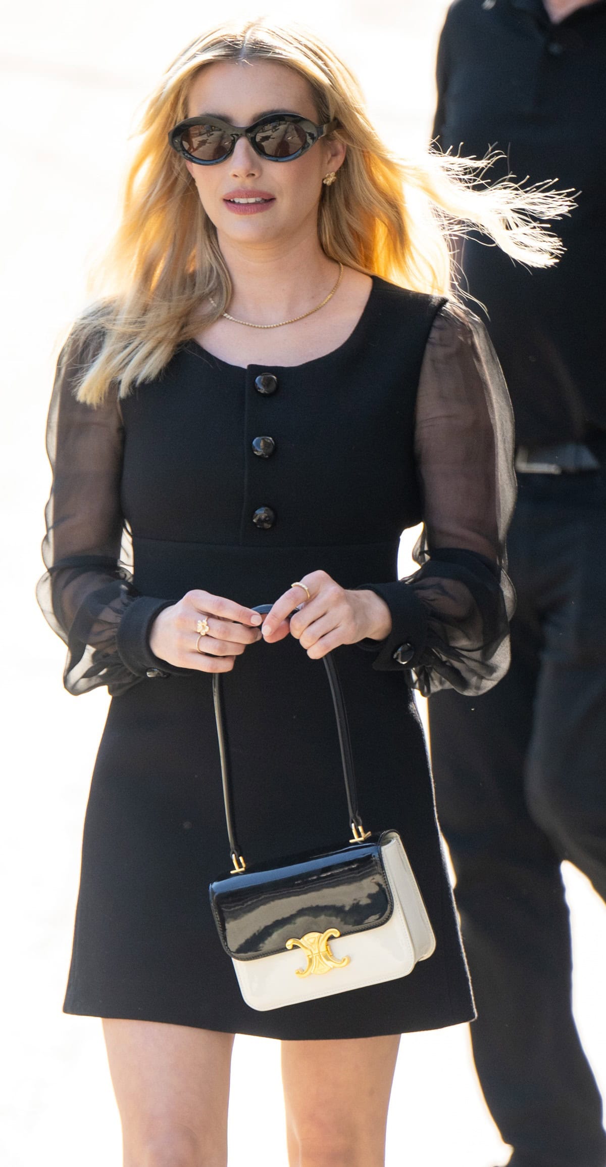 Emma Roberts effortlessly exudes elegance in a classic Celine little black dress paired with a chic black and white Celine bag from the Fall 2024 collection