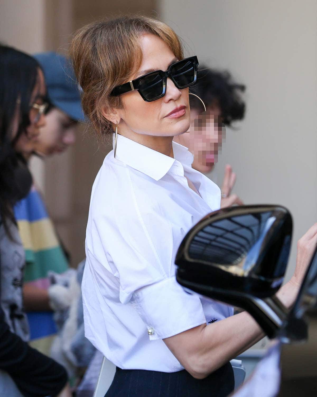 Jennifer Lopez adds bling to her black-and-white office look with Jennifer Fisher hoop earrings and hides her eyes behind James Oro sunglasses