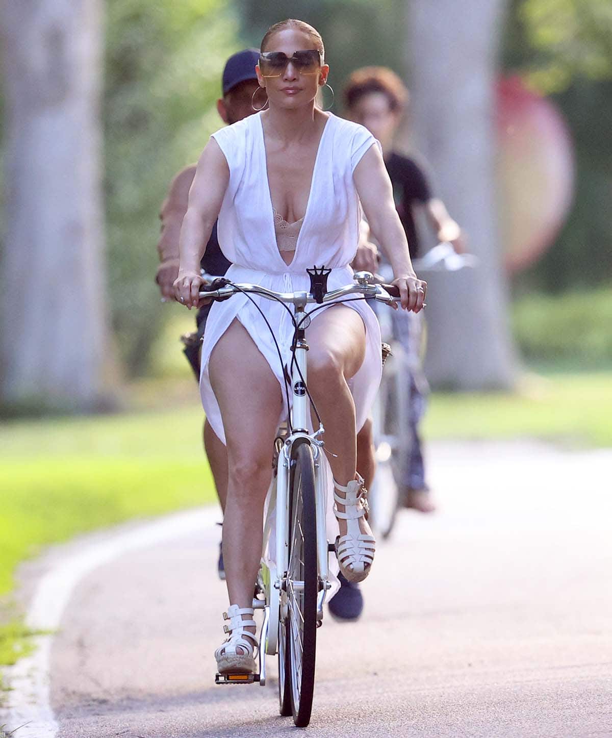 Jennifer Lopez goes biking in a breezy white jumpsuit featuring a navel-deep plunging neckline and thigh-high slits