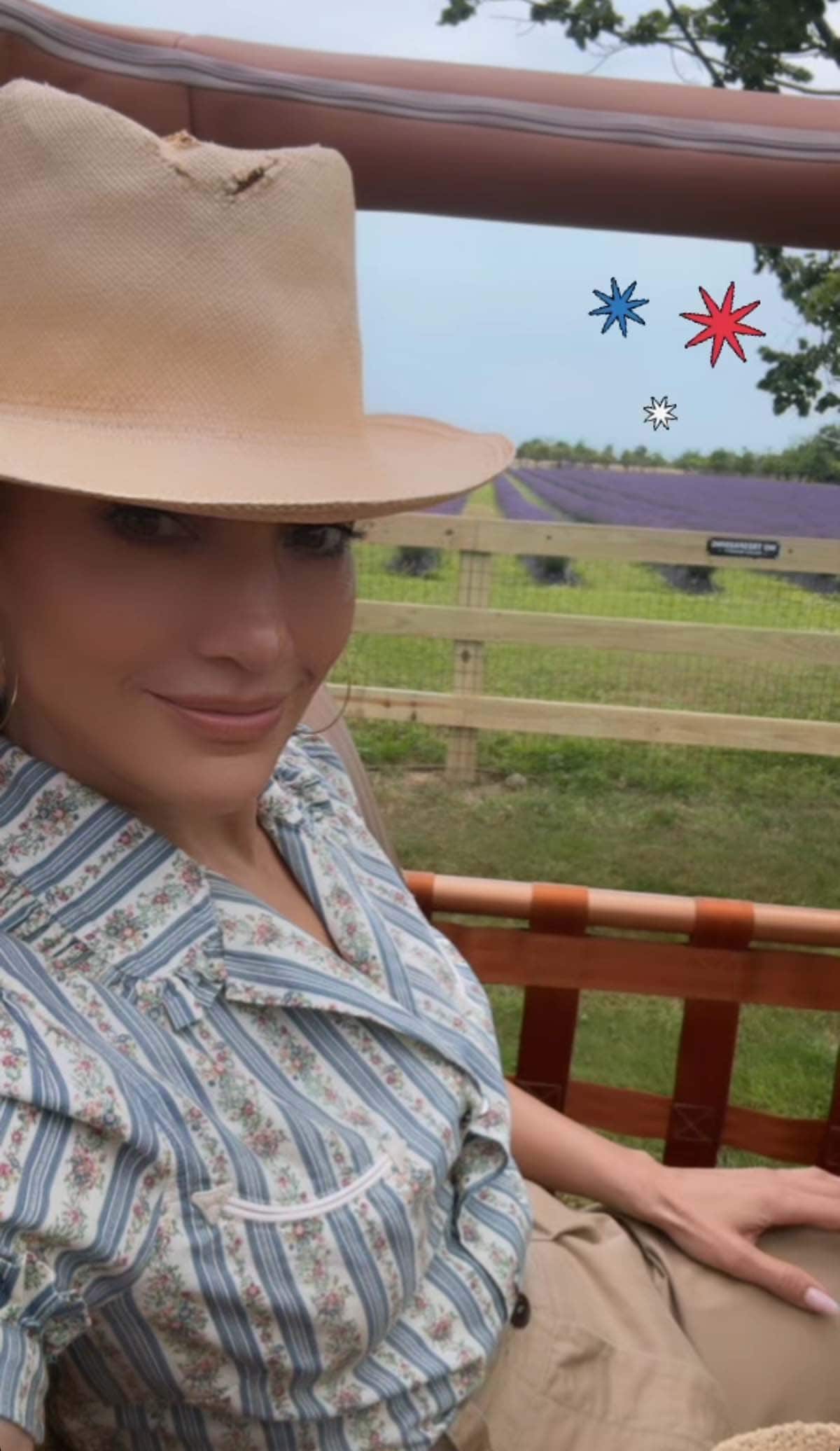 Jennifer Lopez shares a selfie wearing a straw top hat, Jennifer Fisher hoop earrings, and neutral makeup