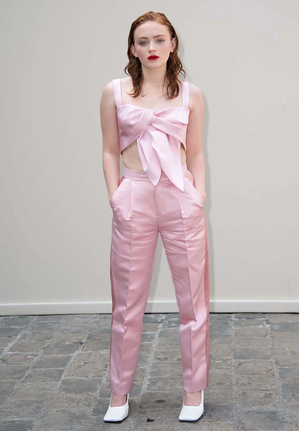 Sadie Sink wears a coquette pink bralette, twisted to form a large bow, and teams it with matching pink tapered pants at Ashi Studio Haute Couture Fall/Winter fashion presentation