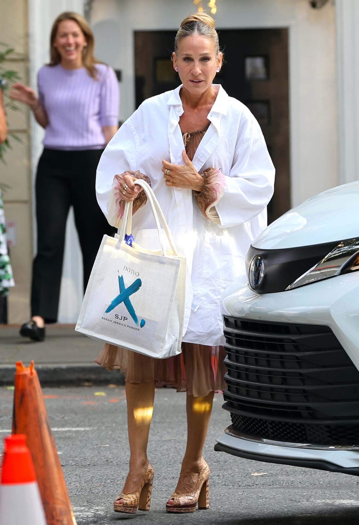 Sarah Jessica Parker wears an oversized white shirt over a sheer ruffled dress with bishop long sleeves