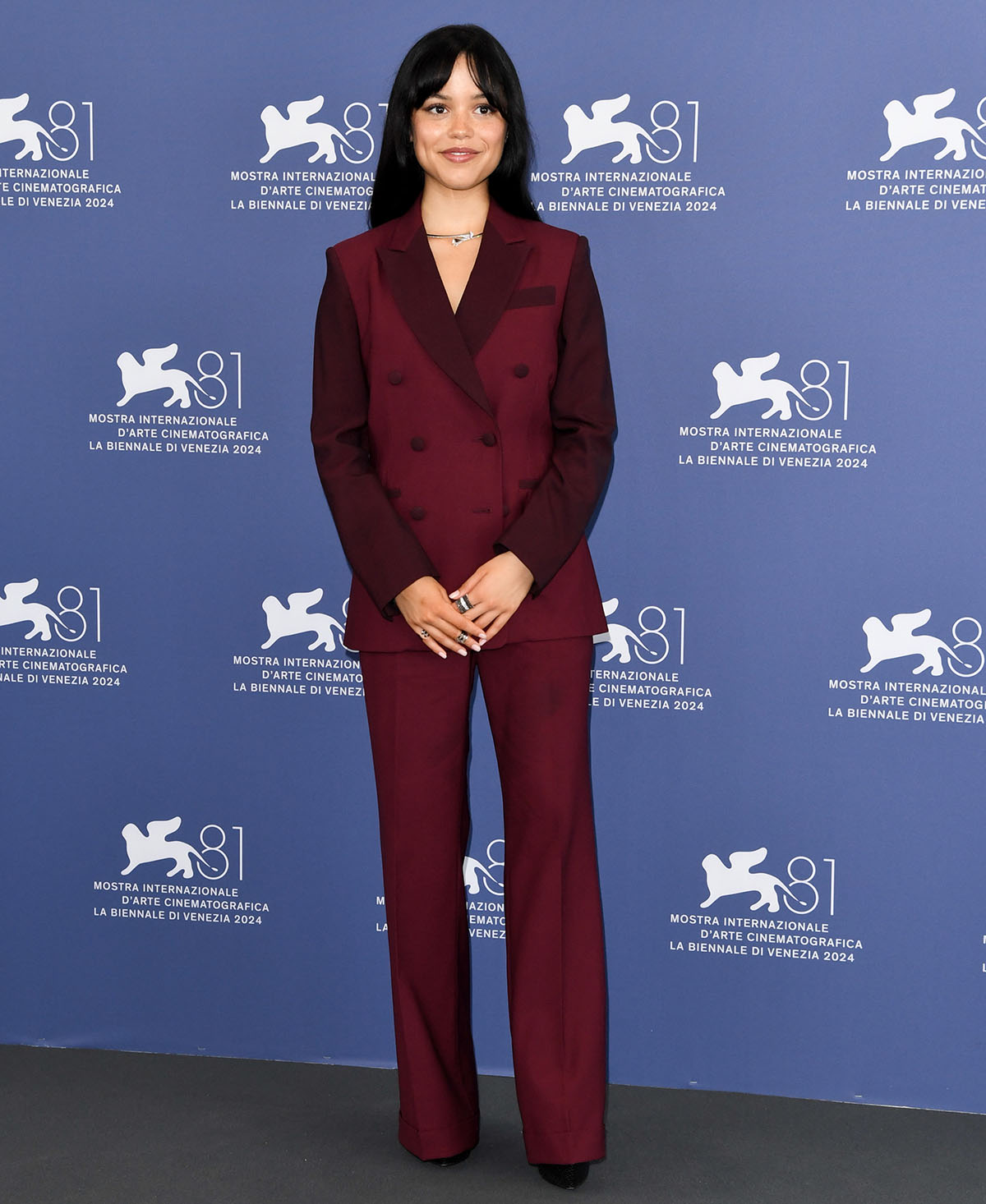 Jenna Ortega power dresses in a burgundy Paul Smith suit at the Beetlejuice Beetlejuice Venice Film Festival photocall