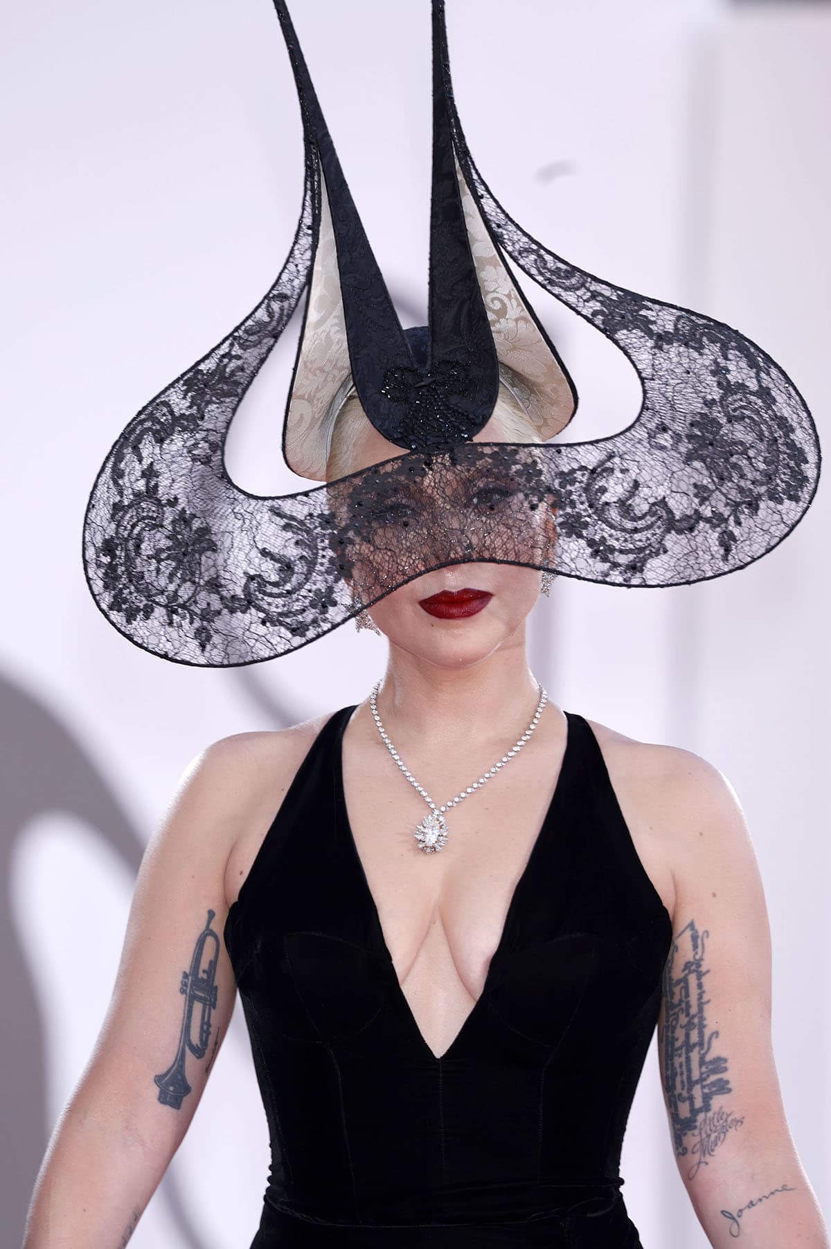 Lady Gaga injects her signature unconventional style into the glamorous Dior gown by wearing the Philip Treacy Fall 2001 “The Lace Wing” hat