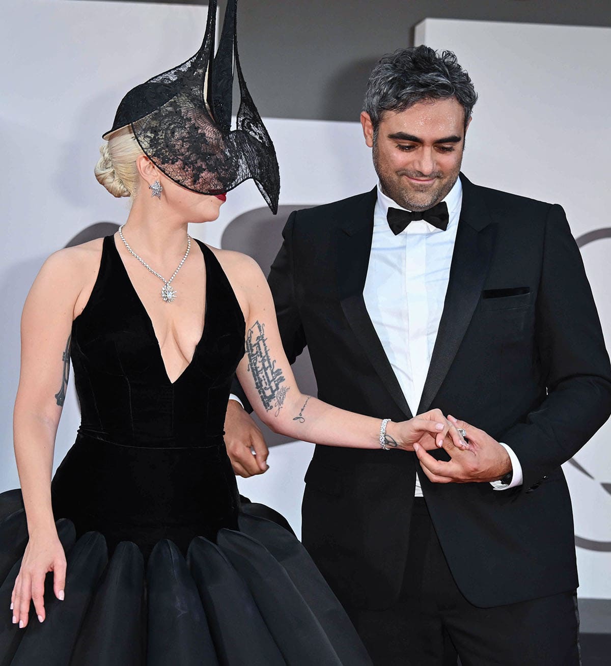 Lady Gaga and her fiancé, Michael Polansky, share a moment on the red carpet as she shows off her stunning $578,000 engagement ring featuring an eight-carat, oval-cut diamond solitaire set in platinum