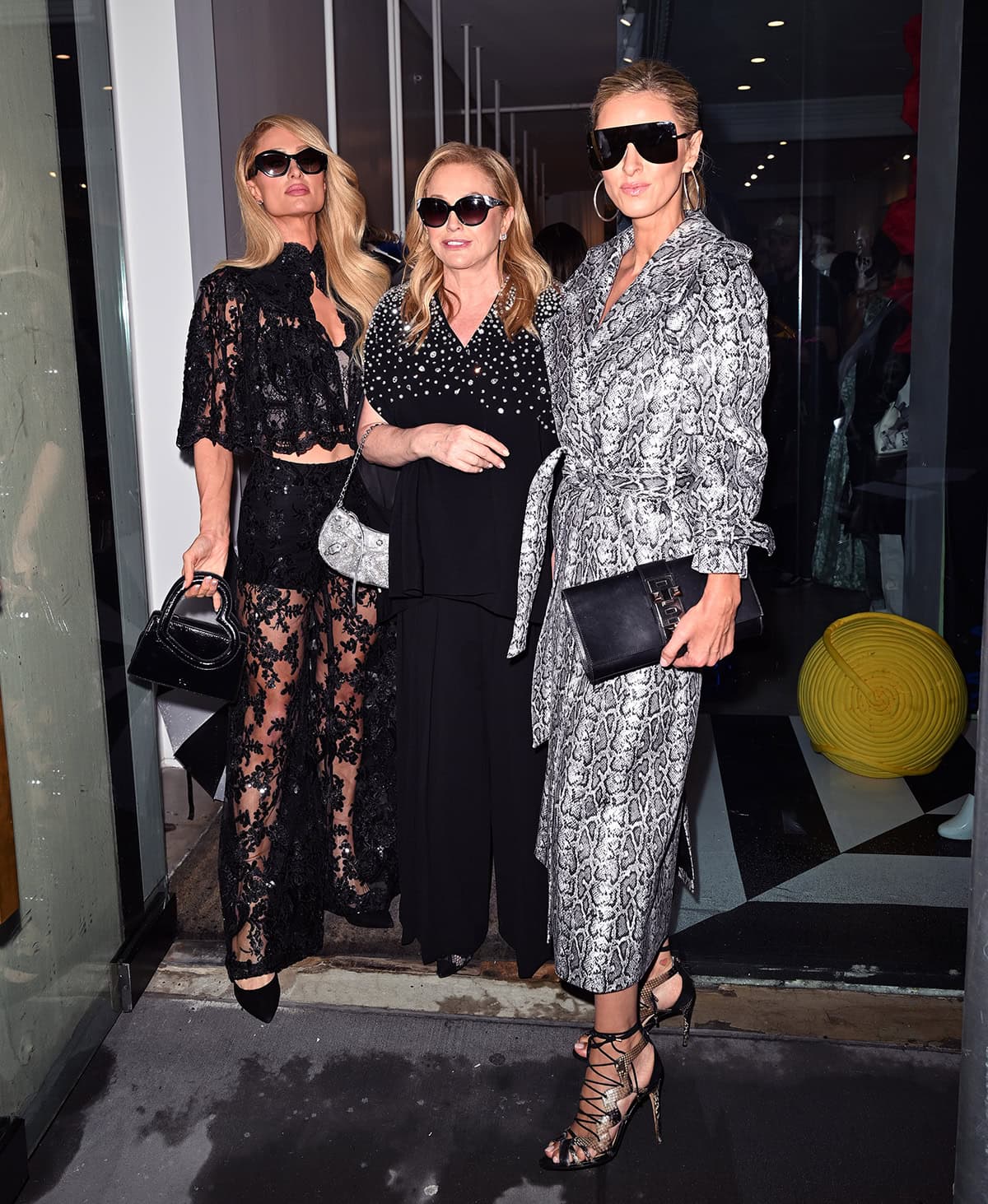 Paris Hilton attends the Alice + Olivia New York Fashion Week runway show in a black lace cape and skirt combo with her mom, Kathy and sister, Nicky