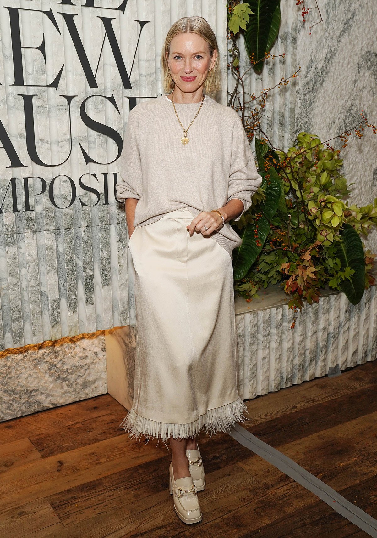 Naomi Watts looks elegant in a loose-fitting sweater tucked into a velvet midi skirt with bohemian fringe trims