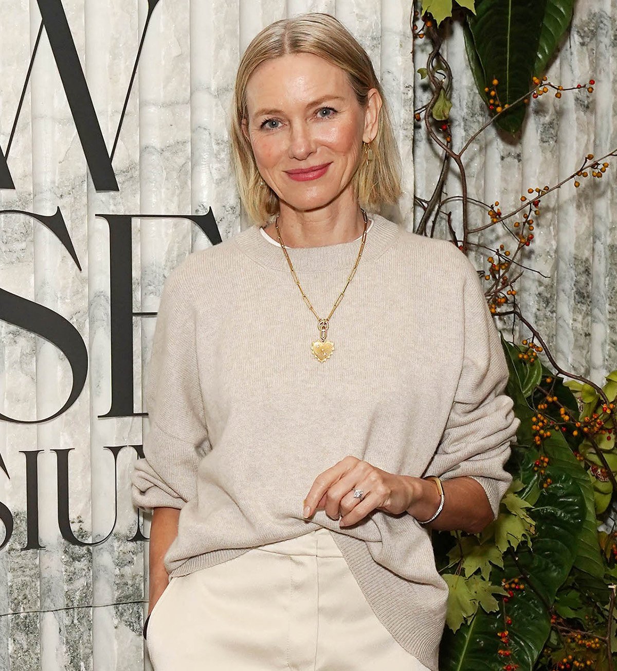 Naomi Watts elevates her monochrome ensemble with a gold necklace, gemstone hook earrings, bracelets, and rings