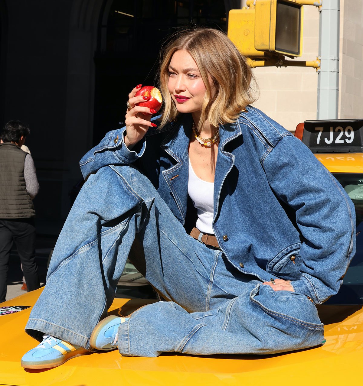 Gigi Hadid wears the same Adidas sneakers and baggy jeans this time with a white tank top and a denim jacket