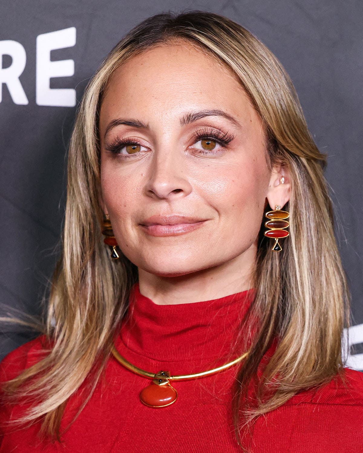 Nicole Richie complements her red dress with red and earth-tone earrings and a necklace from her jewelry label, House of Harlow