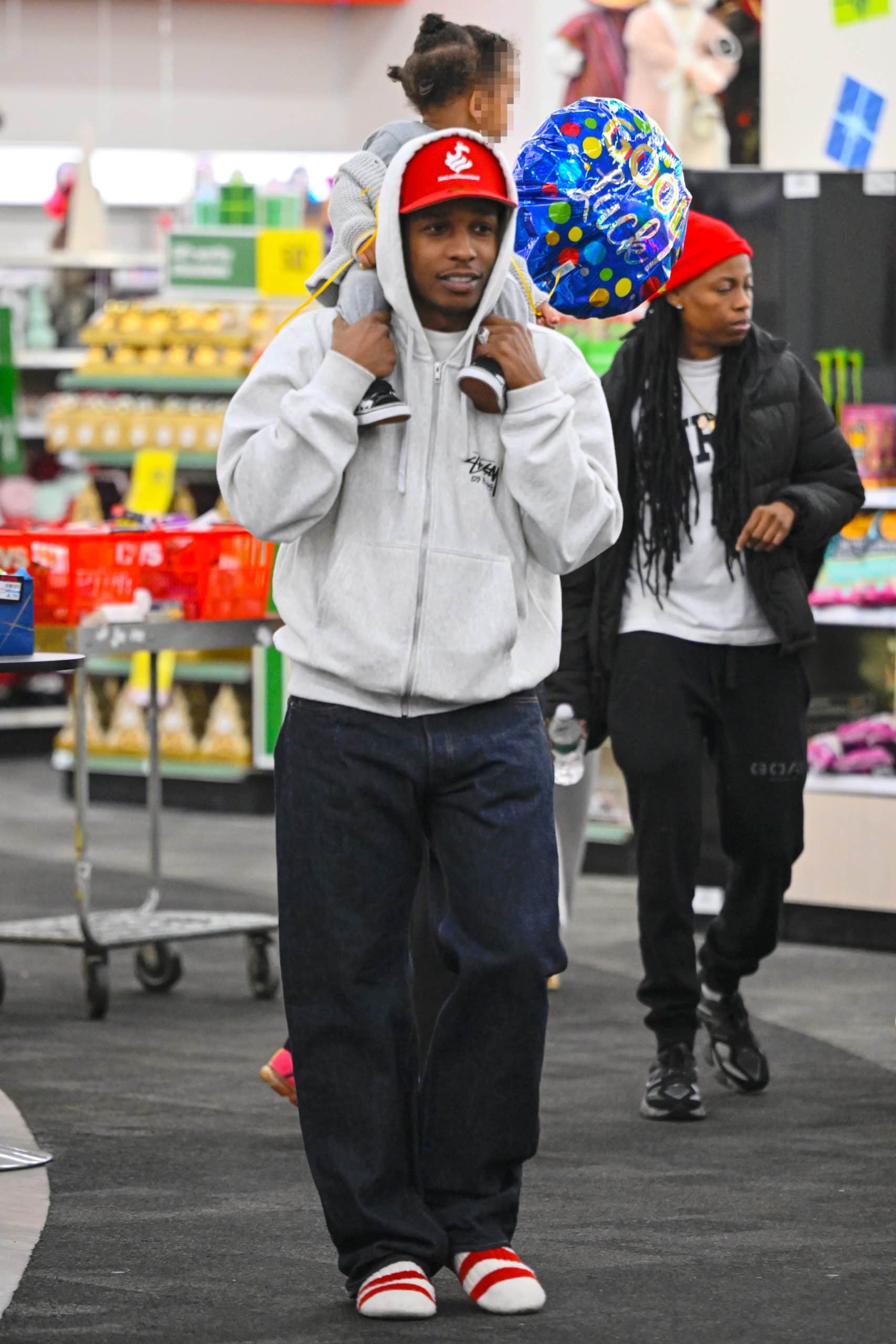 A$AP Rocky keeps things low-key in a light gray Stussy jacket, jeans, and red-and-white striped shoes