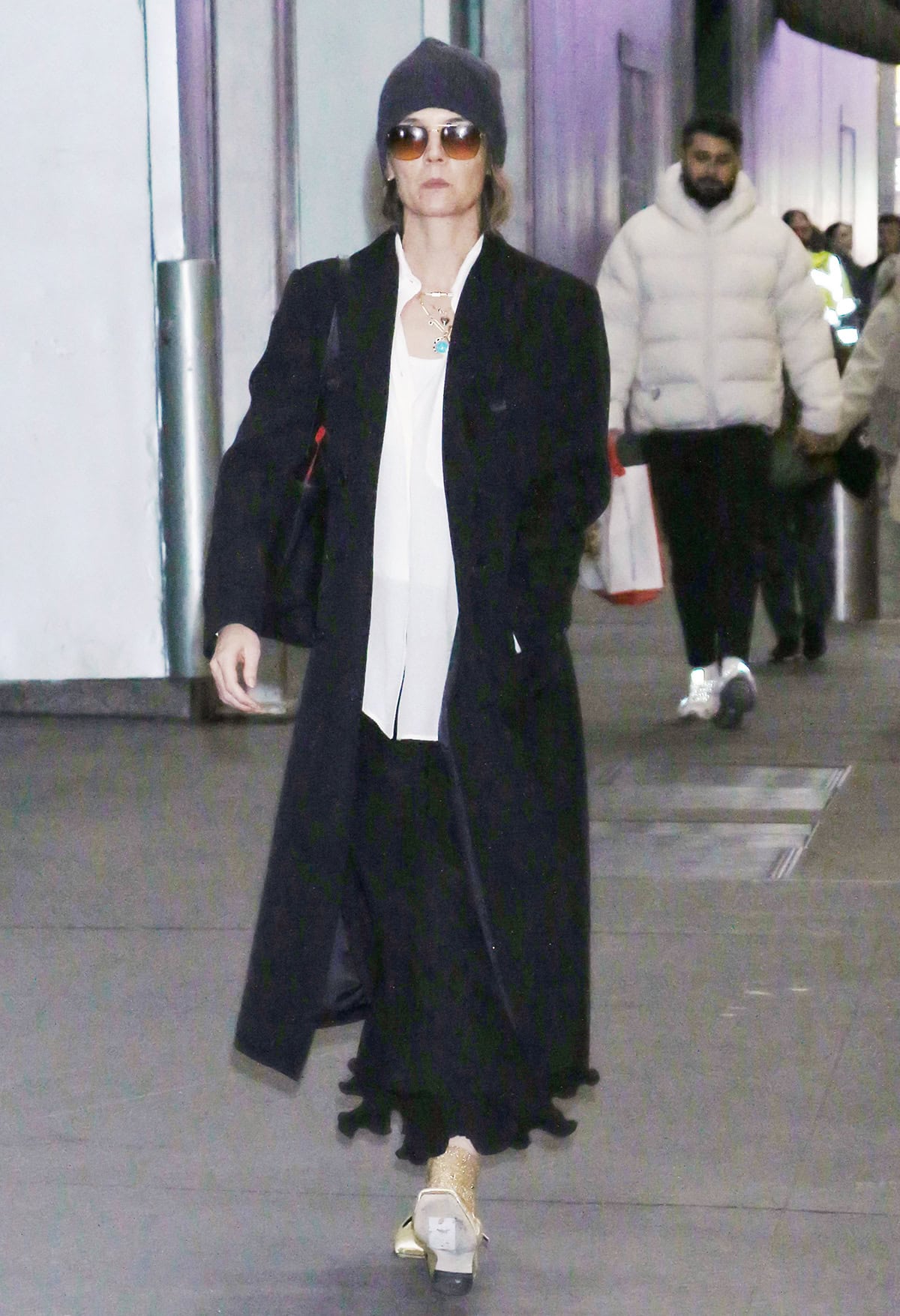 Katie Holmes embraces preppy style in a loose-fitting white shirt, a black maxi skirt with a flounce hem, and a black coat